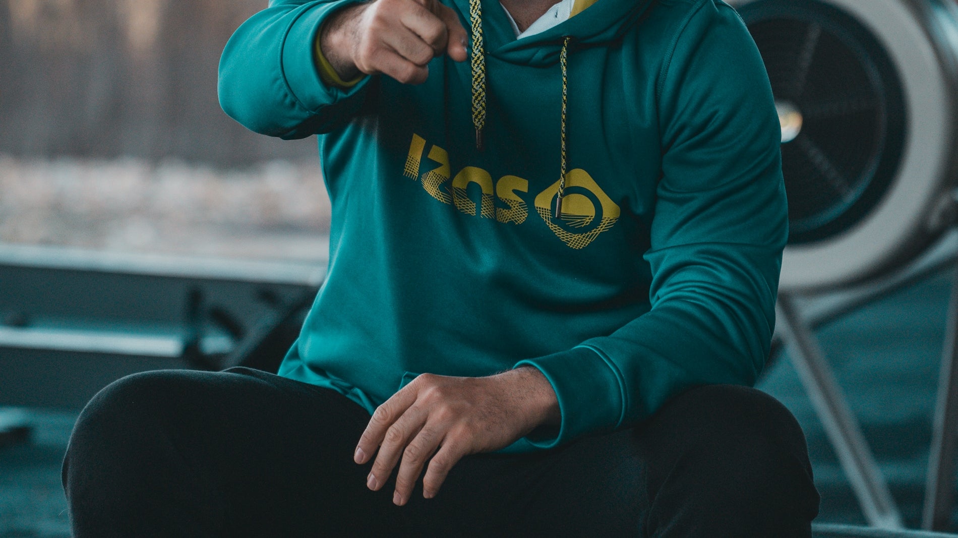 A man in a green hoodie sitting on a tire