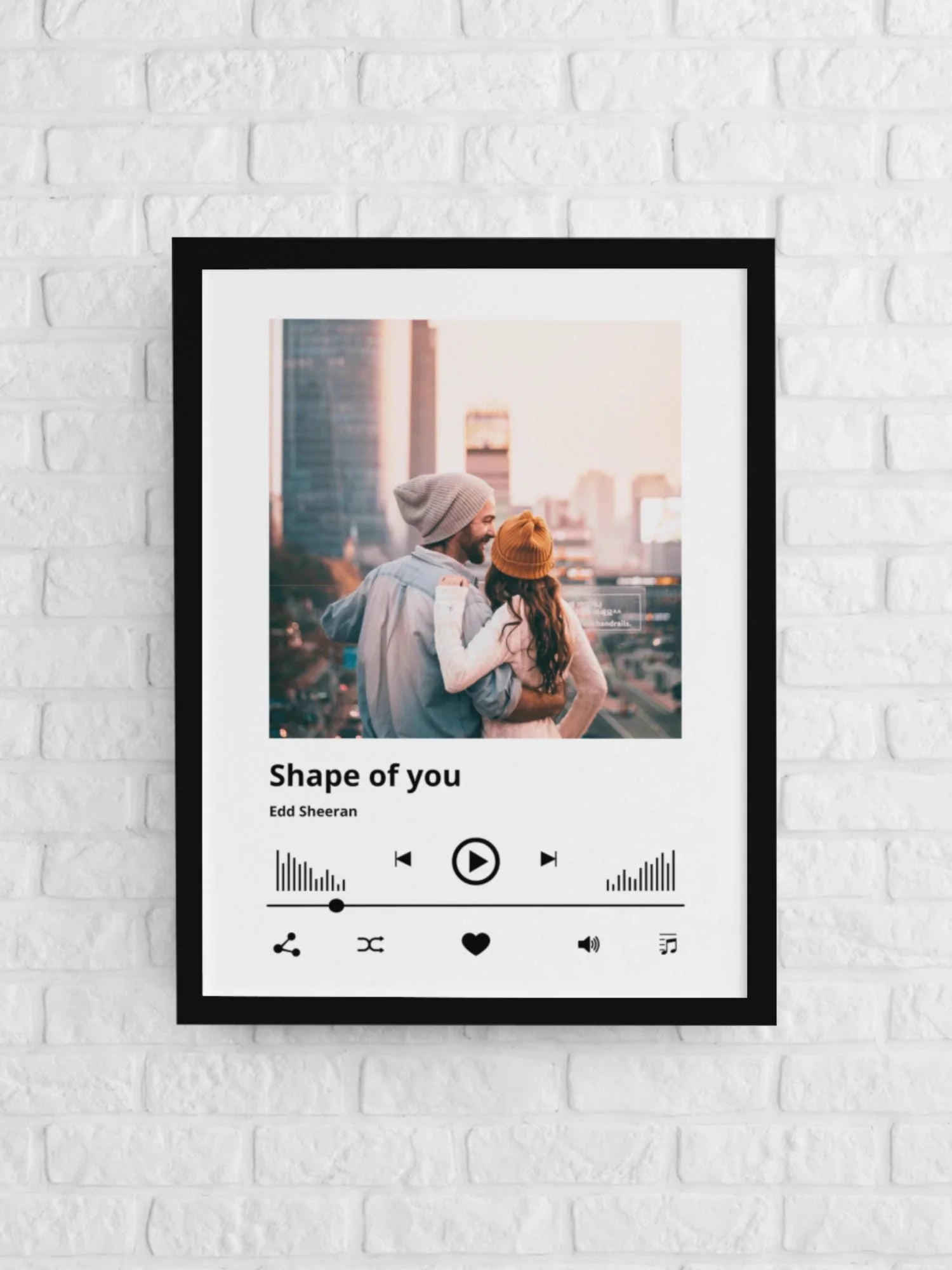 Personalizowany plakat z piosenką 'Shape of You' Edd Sheeran – idealny prezent dla par, wiszący na białej ścianie z cegieł.