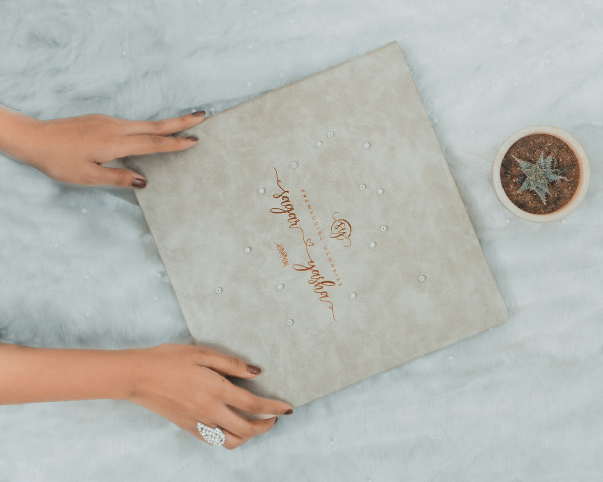 a woman's hands holding a wedding ring next to a box