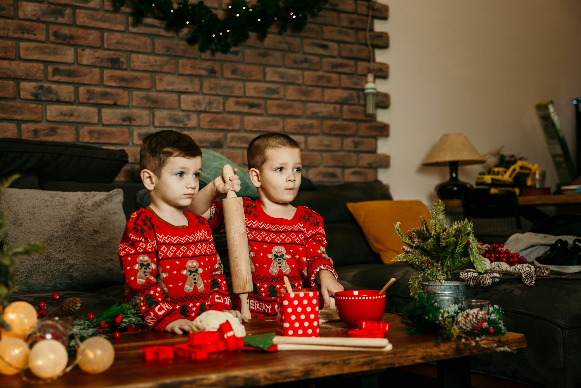 two young boys sitting on a couch in front of a christmas tree